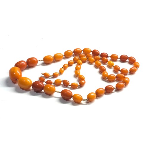 102 - Antique egg yolk amber bead necklace largest bead measures approx 25mm by 19mm graduated beads weigh... 