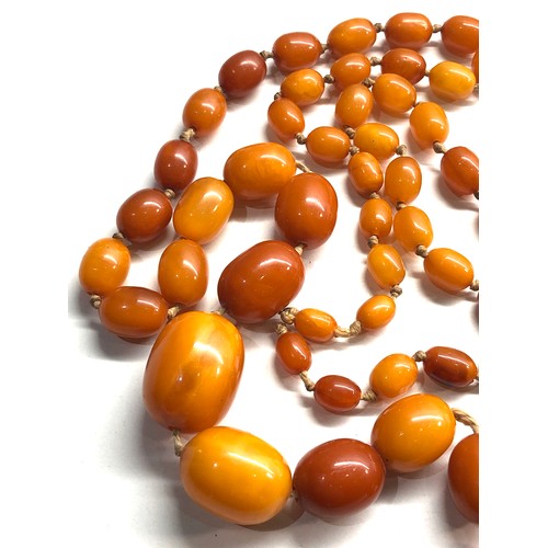 102 - Antique egg yolk amber bead necklace largest bead measures approx 25mm by 19mm graduated beads weigh... 