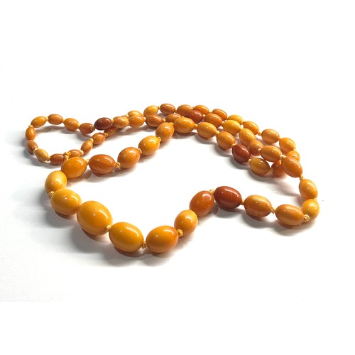 103 - Antique egg yolk amber bead necklace largest bead measures approx 20mm by 15mm graduated beads weigh... 