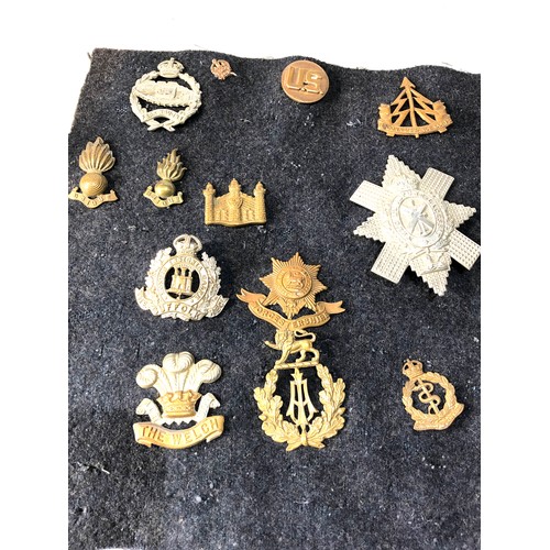 352 - collection of military cap badges on old cloth