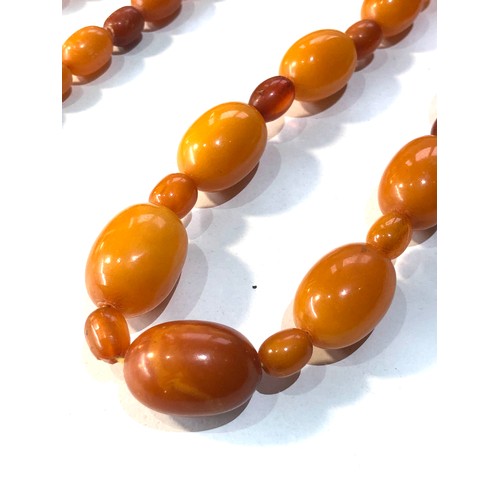 236 - Antique egg yolk amber bead necklace weight 47g largest bead measures approx 22mm by 15mm