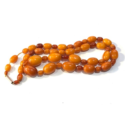 236 - Antique egg yolk amber bead necklace weight 47g largest bead measures approx 22mm by 15mm