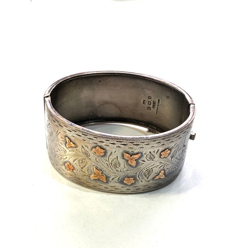 471 - Victorian silver and gold inlaid cuff bangle measures approx 6.5cm by 5.3cm and 3.1cm wide in good c... 