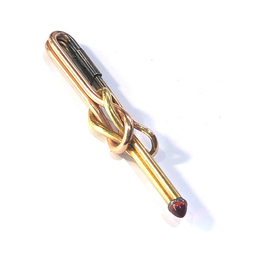 189 - 9ct gold knot tie clip with garnet set tip weight 9g acid tested as 9ct gold not hallmarked