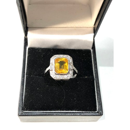 108 - Platinum yellow sapphire and diamond halo and shoulders ring set with central yellow sapphire measur... 