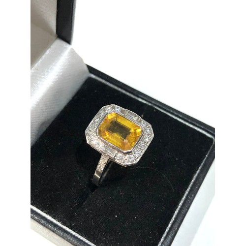 108 - Platinum yellow sapphire and diamond halo and shoulders ring set with central yellow sapphire measur... 