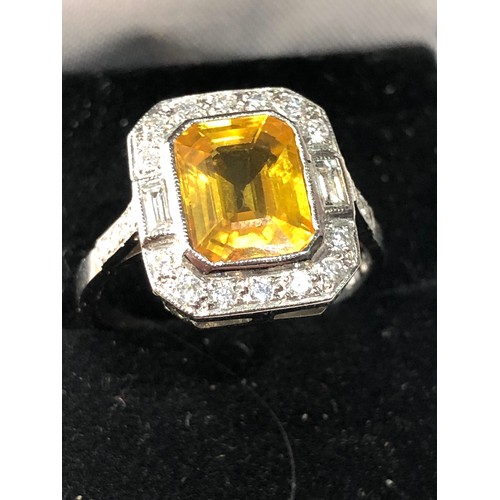 108 - Platinum yellow sapphire and diamond halo and shoulders ring set with central yellow sapphire measur... 