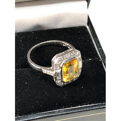 108 - Platinum yellow sapphire and diamond halo and shoulders ring set with central yellow sapphire measur... 