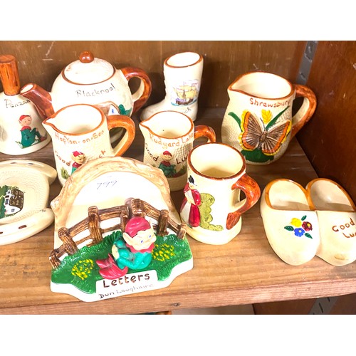 25 - Shelf of holiday souvenir pottery / china