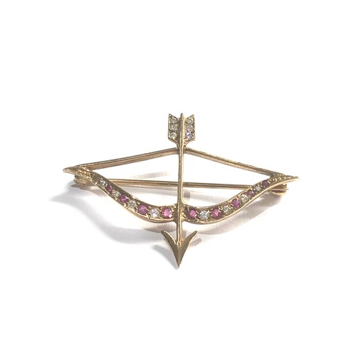 99 - 9ct gold bow & arrow brooch set with ruby and white sapphires measures approx 4.2cm by 3cm weight 3.... 