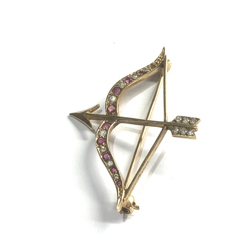 99 - 9ct gold bow & arrow brooch set with ruby and white sapphires measures approx 4.2cm by 3cm weight 3.... 