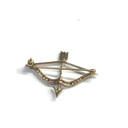 99 - 9ct gold bow & arrow brooch set with ruby and white sapphires measures approx 4.2cm by 3cm weight 3.... 