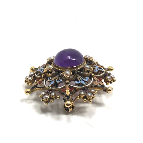 98 - An antique 15 carat gold  with enamel decoration, and set with an amethyst cabochon surrounded by pe... 