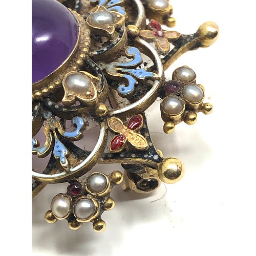 98 - An antique 15 carat gold  with enamel decoration, and set with an amethyst cabochon surrounded by pe... 