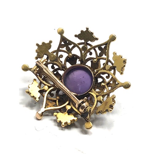 98 - An antique 15 carat gold  with enamel decoration, and set with an amethyst cabochon surrounded by pe... 