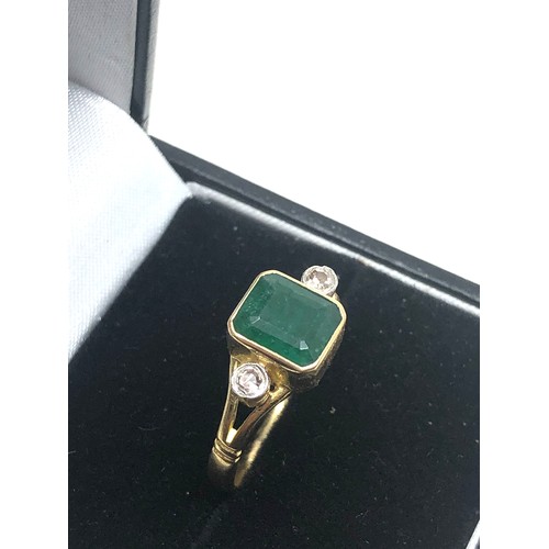 86 - 18ct gold emerald & diamond ring central emeral measures approx 8mm by 6mm with a diamond either sid... 