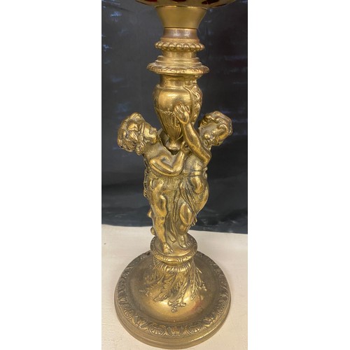 100A - Brass oil lamp, cranberry shade and font with cherubs, approximate height 28 inches