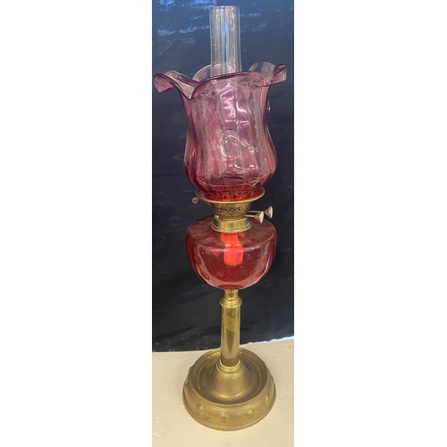 100B - Brass oil lamp cranberry shade and font, approximate height  27 inches