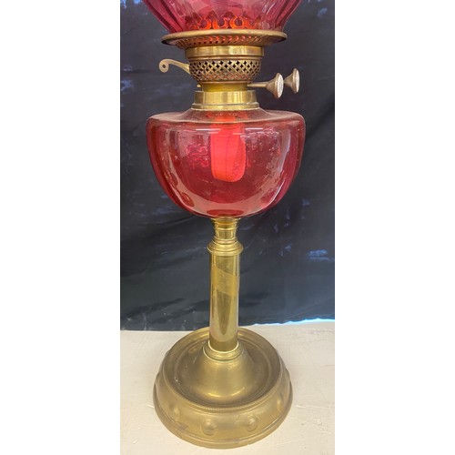 100B - Brass oil lamp cranberry shade and font, approximate height  27 inches