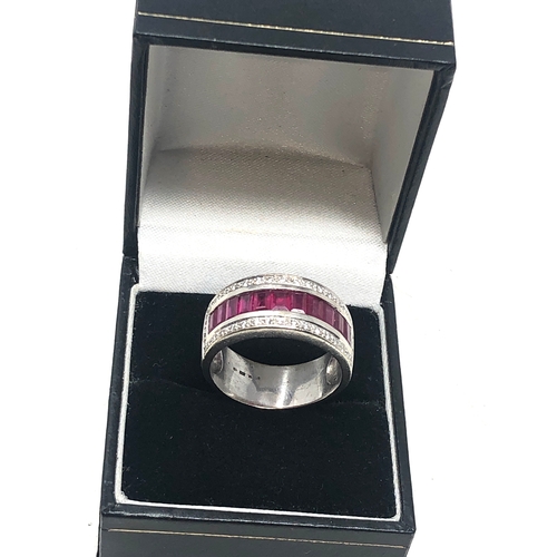 67 - 18ct white gold ruby and diamond band ring set with a row of rubies with diamond halo weight 8.7g