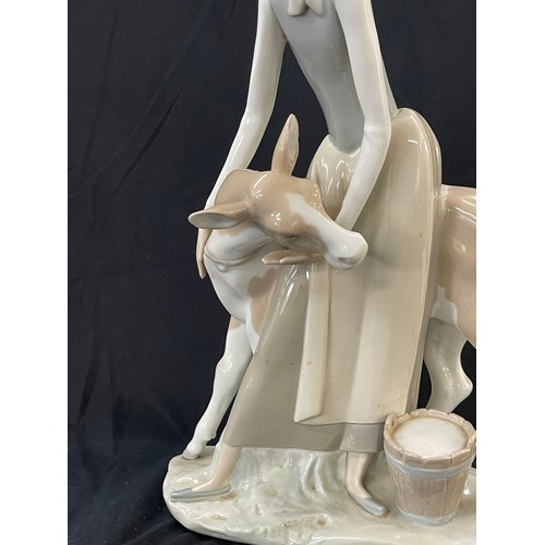 45 - Lladro Porcelain Farmer Girl Miling Cow measures approximately 13 inches tall