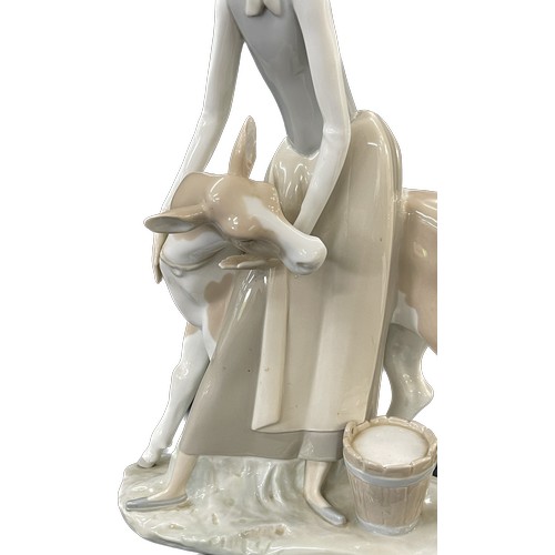 45 - Lladro Porcelain Farmer Girl Miling Cow measures approximately 13 inches tall