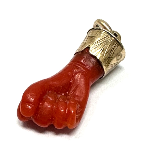 122 - Antique gold mounted coral fisted hand pendant