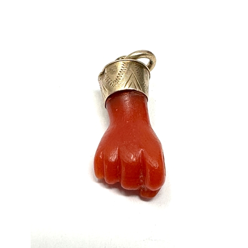 122 - Antique gold mounted coral fisted hand pendant