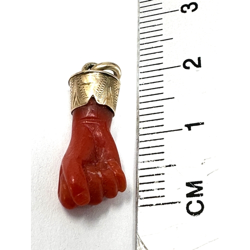 122 - Antique gold mounted coral fisted hand pendant