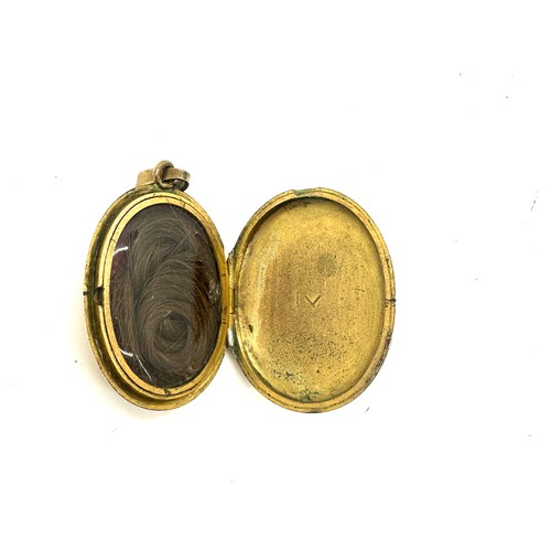 560 - Antique yellow metal and enamel locket containing a lock of hair weight 18grams size 3.5cm by 2.6cm