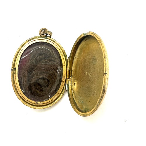 560 - Antique yellow metal and enamel locket containing a lock of hair weight 18grams size 3.5cm by 2.6cm