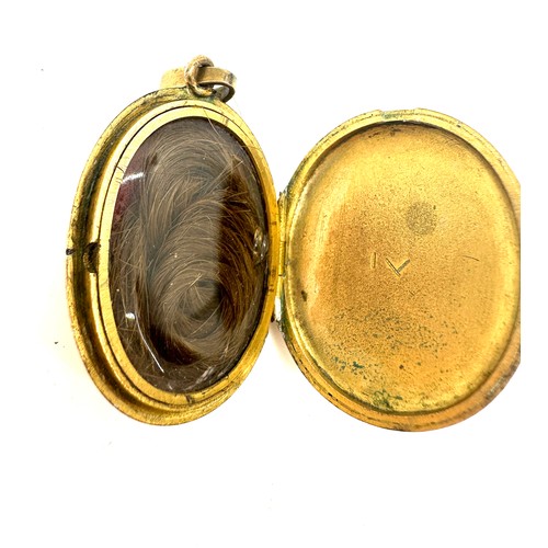 560 - Antique yellow metal and enamel locket containing a lock of hair weight 18grams size 3.5cm by 2.6cm