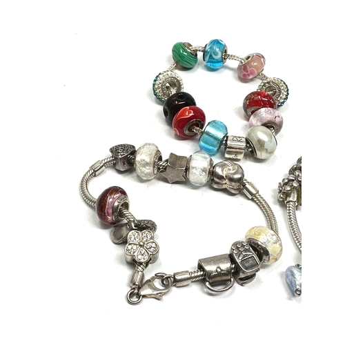 301 - Three silver mixed brand charm bracelets and charms (124g)