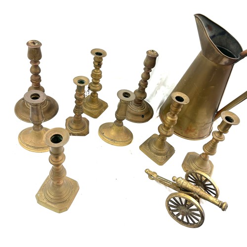 113 - Selection of antique and later brass candle sticks and a large water jug, canon ornament