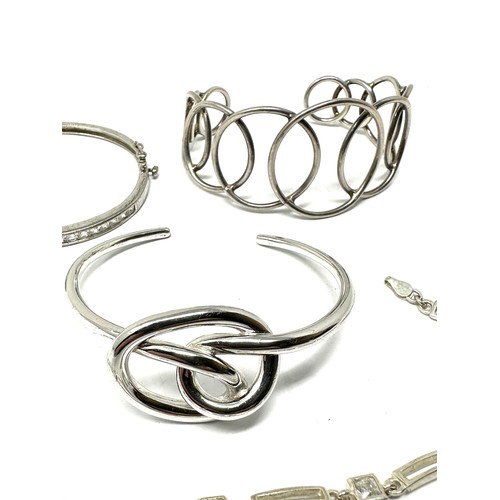 349 - Four silver bangles & bracelet including CZ (74g)