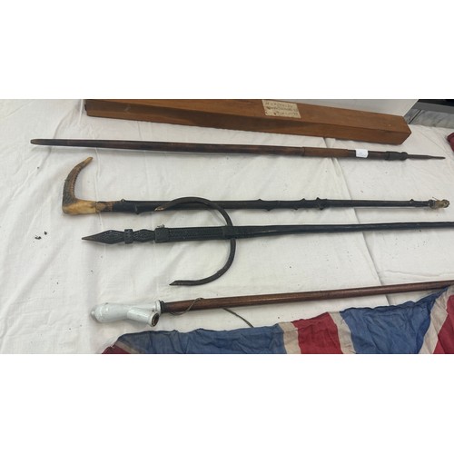 140 - Selection of walking sticks, spear etc 2 union jack flags