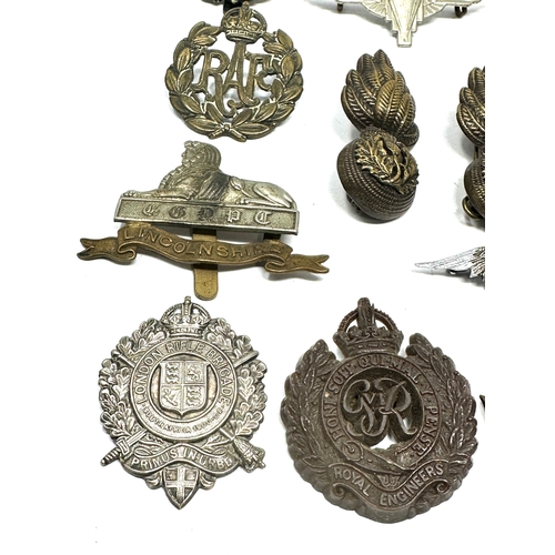 335 - 21 military cap badges and badges