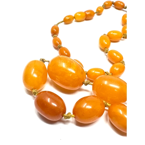 69 - Vintage long egg yolk amber bead necklace measures approx  115 cm long weight approx 52g