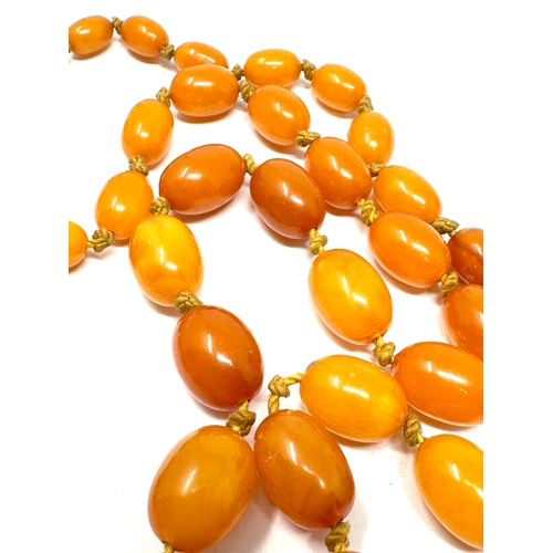 69 - Vintage long egg yolk amber bead necklace measures approx  115 cm long weight approx 52g