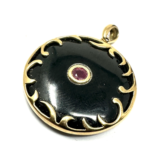 78 - 9ct gold ruby 7 black stone pendant measures approx 2.6cm dia weight 6.9g