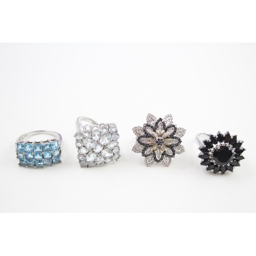 313 - Four silver stone set dress rings including diamond and topaz (35g)