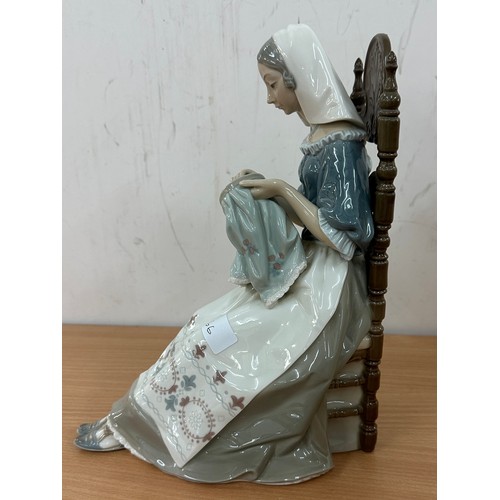 569 - Lladro lady figurine, of a lady knitting on a chair 11 inches tall