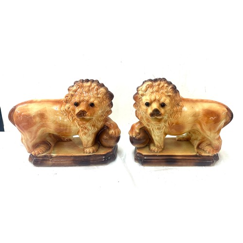 273 - Pair of Staffordshire lions 1920's glass eyes, paw on balls. By Lancaster and Sons LTD. Hanley Staff... 