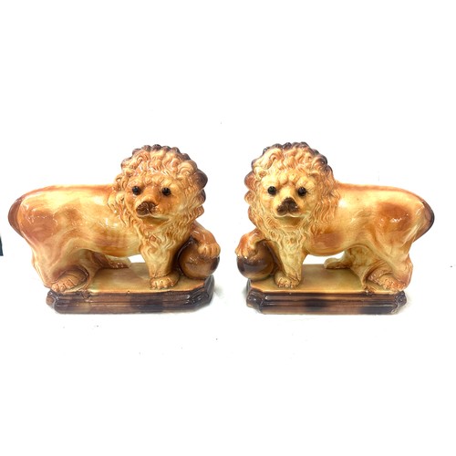 273 - Pair of Staffordshire lions 1920's glass eyes, paw on balls. By Lancaster and Sons LTD. Hanley Staff... 