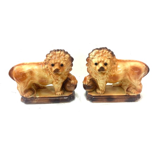 273 - Pair of Staffordshire lions 1920's glass eyes, paw on balls. By Lancaster and Sons LTD. Hanley Staff... 