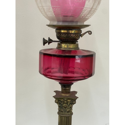 312 - Antique column base oil lamp with cranberry glass, total height 30 inches