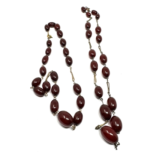 56 - 2 cherry amber/bakelite bead necklaces yellow metal chain weight 36g