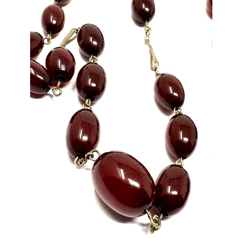 56 - 2 cherry amber/bakelite bead necklaces yellow metal chain weight 36g