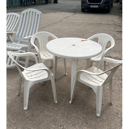 100E - Plastic outdoor table and for chairs along with two plastic outdoor lounging chairs