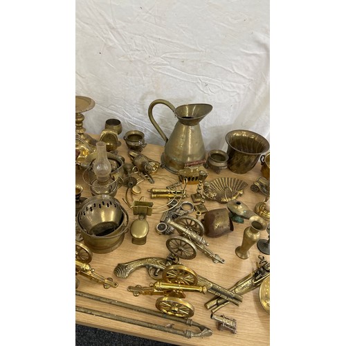 102 - Large selection of brass ware items to include jugs, ornaments, oil lamps, canons, egg timer etc